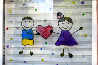 Crteži na prozoru dječjeg vrtića, djeca se igraju Crteži na prozoru dječjeg vrtića. Ilustracije i crteži djece.