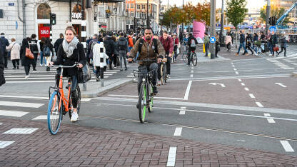 Grupa ljudi vozi bicikle u Amsterdamu Amsterdam, Nizozemska: Grupa biciklista vozi bicikle po ulici. Biciklizam u gradu. Ljudi koriste bicikle za vožnju.