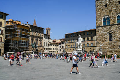 Firenze, Italija: Turisti na trgu. Neptunova fontana. Firenze, Italija: Turisti istražuju grad. Neptunova fontana na Piazza della Signoria. Ljudi šetaju trgom. Zgrade u centru grada.