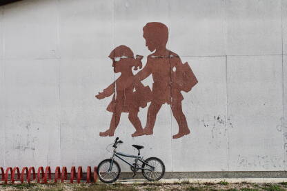 Školovanje djece Mural na zidu škole, silueta dječaka i djevojčice, bicikl naslonjen na zid