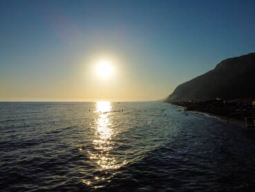 Turisti plivaju u moru tokom zalaska sunca, snimak dronom. Grupa ljudi se zabavlja u vodi. Ljudi na ljetnom godišnjem odmoru. Uživanje u vodi.