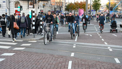 Grupa ljudi vozi bicikle u Amsterdamu Amsterdam, Nizozemska: Grupa biciklista vozi bicikle po ulici. Biciklizam u gradu. Ljudi koriste bicikle za vožnju.