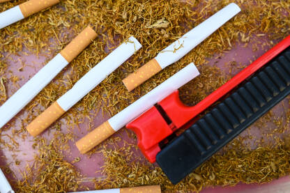 Osušeni duhan i cigarete u kutiji. Mašinica za punjenje cigareta. Loše navike i ovisnost. Pušenje.