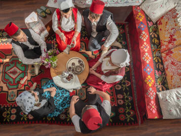 Bajramska kafa Dječaci i djevojčice u tradicionalnoj nošnji sjede za sofrom, sinijom