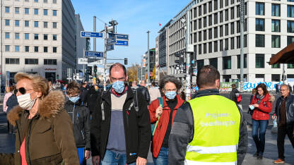 Ljudi sa maskama na ulici Berlin, Njemačka: Ljudi s maskom za lice hodaju ulicom. Covid-19 zaštita. Grupa ljudi s medicinskim maskama u gradu. Zaštita od epidemije korona virusa.