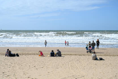 Ljudi na plaži na obali Sjevernog mora u Hagu, Nizozemska. Pješčana plaža u Scheveningenu. The Hague ili Den Haag. Valovi na moru.