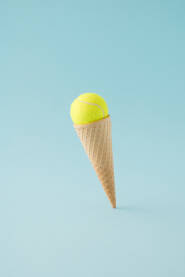 Kornet za sladoled s lopticom Kornet za sladoled s lopticom za tenis na plavoj pozadini.