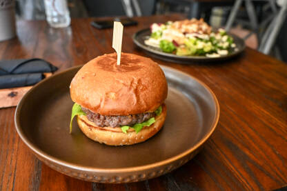 Hamburger serviran na stolu u restoranu. Brza hrana.