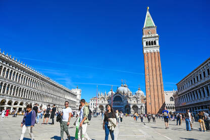 Venecija, Italija: Ljudi šetaju glavnim trgom. Piazzetta San Marco. Popularna turistička destinacija. Zvonik, Bazilika svetog Marka i Duždeva palača u centru grada.