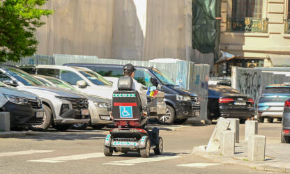 Muškarac sa invaliditetom se vozi u kolicima na ulici. Osobe sa invaliditetom u saobraćaju. Kretanje osoba sa invaliditetom.