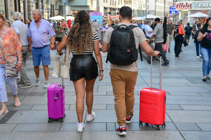 Turisti šetaju gradom s prtljagom. Putnici nose kofere i ruksake. Putnici hodaju s prtljagom prema stanici. Ljudi koji putuju s torbama.