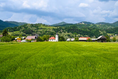 Prekrasan krajolik Prekrasan krajolik sela sa crkvom i zelenim poljem u proljeće. Žitarice rastu u polju.