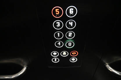Tipke u liftu u zgradi. Brojevi. Tipke u liftu u zgradi. Osvjetljena upravljačka tabla u liftu. Brojevi na tipkama.