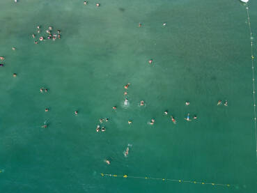 Turisti plivaju u moru. Grupa ljudi se zabavlja u vodi tokom ljetnog odmora. Ljudi uživaju u moru.