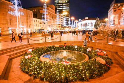 AK1_2276 Advent u Zagrebu, Hrvatska. Ukrasi s lampicama na glavnom gradskom trgu. Ljudi se zabavljaju na Adventu na trgu baja Jelačića noću. Fontana Manduševac.