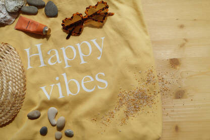 Žuta torba za plažu sa maočalama za sunce, kremom za sunčanje i pletenom lepezom.