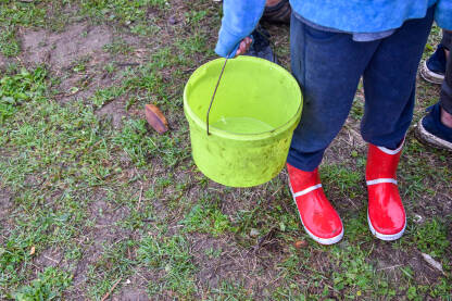 Dijete drži kantu Dijete stoji u redu za hranu i drži plastičnu kantu. Dijete na izbjegličkoj/migrantskoj ruti. Dijete čeka hranu u improvizovanom kampu u Velikoj Kladuši, Bosna i Hercegovina.