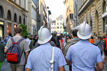 Policajci patroliraju gradom u Italiji. Italijanski policajci u uniformama s bijelim kacigama. Policija patrolira gradskim ulicama.