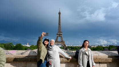 Pariz, Francuska: Turisti se fotografišu ispred Eiffelovog tornja. Popularna turistička destinacija.