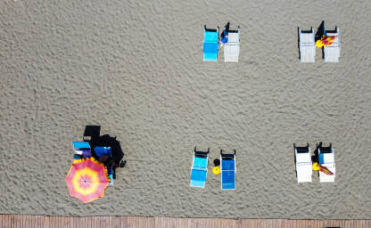 Suncobrani i ležaljke na plaži. Ilustracija godišnjeg odmora, ljeta, sunčanja, turizma i putovanja.