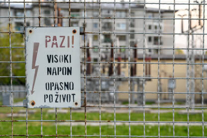 Znak za opasnost od strujnog udara na trafostanici. Znak za opasnost od strujnog udara na trafostanici. Simbol: Znak upozorenja uz trafo stanicu. Natpis: Visoki napon. Rizik za život.