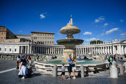 Vatikan: Turisti ispred fontane na trgu svetog Petra. Grupa ljudi na trgu u Vatikanu ispred bazilike sv. Petra.