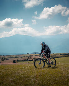 MTB, muškarac vozi brdski bicikl Brdsko planinski biciklizam u Bihaću sa Plješevicom u pozadini.