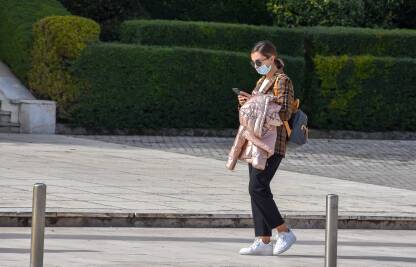Žena sa maskom Žena hoda ulicom sa maskom na licu zbog prevencije širenja virusa korona.