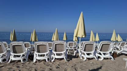 Osunčana pješčana plaža sa ležaljkama i suncobranima, bez ljudi