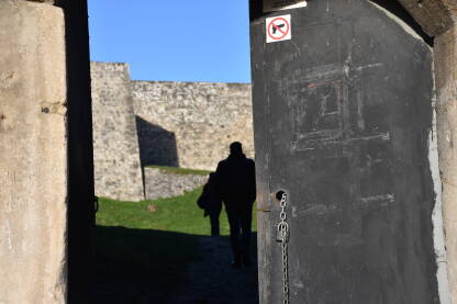 Silueta muškarca Ulaz u tvrđavu sa znakom zabranjivanja nošenja oružja sa siluetom muškarca i žene u pozadini.