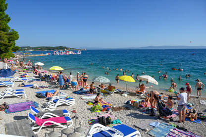 Plaža u Makarskoj puna ljudi Turisti na moru. Ljudi se kupaju i sunčaju u Jadranskom moru. Ljetni odmor. Grupa turista na plaži tokom toplog ljetnog dana. Makarska, Hrvatska.