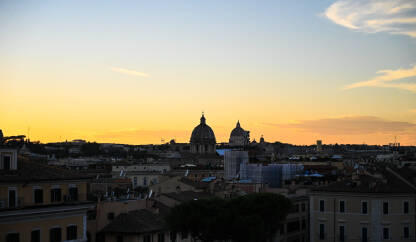 Panoramski pogled na Rim i Vatikan tokom zalaska sunca. Kupole crkvi i katedrala. Silueta zgrada.