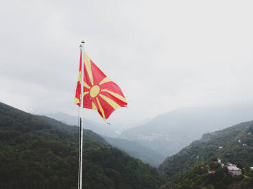 Zastava Sjeverne Makedonije. Zastava Sjeverne Makedonije iznad kanjona. Državna zastava na jarbolu, snimak dronom. Žuto sunce na crvenom polju.