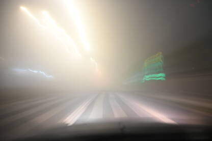 Zamućena fotografija vožnje automobilom po maglovitom vremenu. Zamućena fotografija vožnje automobilom po maglovitom vremenu. Jako zagađenje zraka. Teški uslovi za vožnju noću. Pogled na cestu kroz vjetrobransko staklo automobila. Magla.