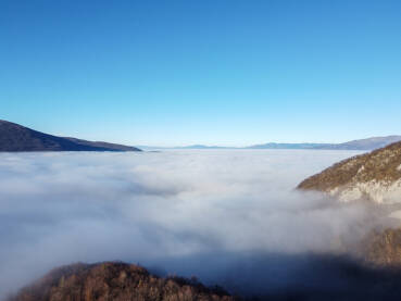 Magla i oblaci prekrivaju dolinu, snimak dronom. Zagađenje zraka. Let iznad oblaka.
