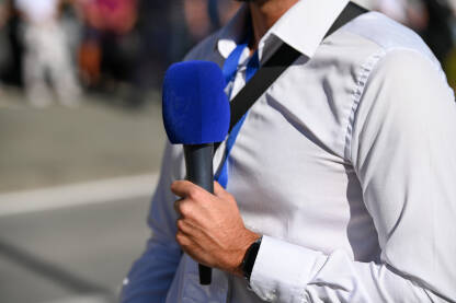 Novinar drži mikrofon dok izvještava uživo. TV reporter.