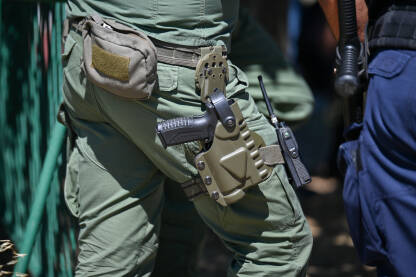 Pištolj na pojasu policajca. Pištolj u futroli pripadnika specijalnih policijskih snaga. Oružje policajca.