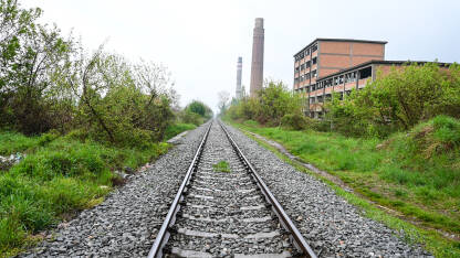 Željeznička pruga u blizini stare fabrike. Željezničke šine pored napuštenog industrijskog kompleksa. Željeznička pruga u blizini stare fabrike.