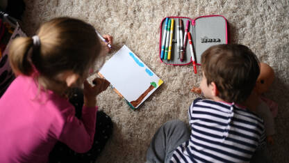 Djevojčica se igra sa lutkom u kući. Ruke djevojčice grle lutku. Zaigrana djeca. Sretna djeca se zabavljaju s igračkama.