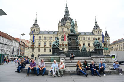 Graz, Austrija: Grupa ljudi na glavnom trgu u centru grada. Graz, Austrija: Grupa ljudi na glavnom trgu u centru grada. Historijske građevine na glavnom trgu ili Hauptplatzu. Stari grad Graz. Erzherzog-Johann-Brunnen fontana.