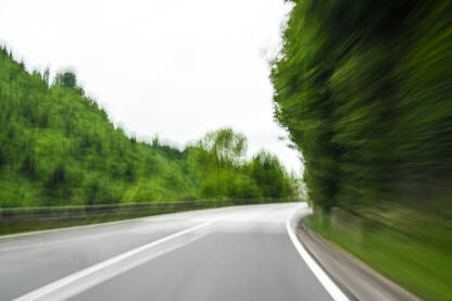 Brza vožnja ulicom Zamućena fotografija automobila koji brzo vozi po cesti u prirodi. Kretanje automobila po asfaltiranoj ulici. Pogled vozača na opasnu vožnju. Koncept: sigurnost, alkohol, brzina.