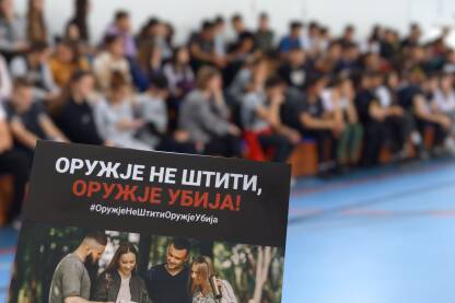 Oružje ne štiti - oružje ubija Brošura "Oružje ne štiti - oružje ubija" u krupnom planu dok su učenici van fokusa.