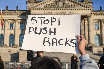 Stop Push Backs Žena na protestima nosi transparent "Stop Push Backs. Promigrantski protesti. Demonstracije. Grupa ljudi na protestu za ljudska prava i slobode.