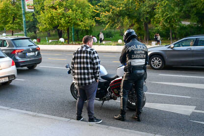 Saobraćajni policajac zaustavlja vozila i provjerava dokumente. Policajac na motociklu zaustavio vozača. Saobraćajni policajac provjerava dokumente vozača. Policajac na poslu.
