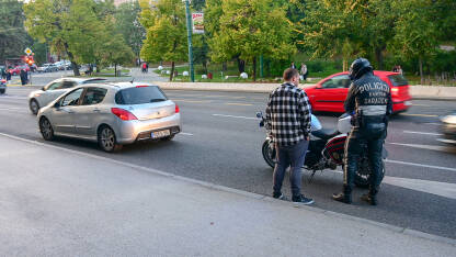 Saobraćajni policajac zaustavlja vozila i provjerava dokumente. Policajac na motociklu zaustavio vozača. Saobraćajni policajac provjerava dokumente vozača. Policajac na poslu.