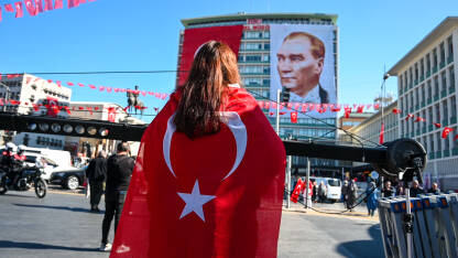 Djevojka ogrnuta zastavom Republike Turske gleda na fotografiju Mustafe Kemala Ataturka. Djevojka ogrnuta zastavom Republike Turske gleda na veliku fotografiju Mustafe Kemala Ataturka, osnivača moderne Turske. Dan državnosti Republike Turske.