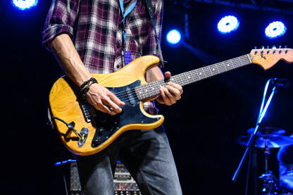 Muzičar svira električnu gitaru Muzičar svira električnu gitaru na festivalu s bendom na bini pod svjetlima. Pjevač i gitarist svira gitaru na rock koncertu uživo. Muzički instrument.