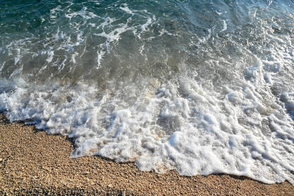AK1_3251 Morski valovi na plaži sa sitnim zlatnim pijeskom. Talasi na obali mora tokom zalaska sunca ljeti.