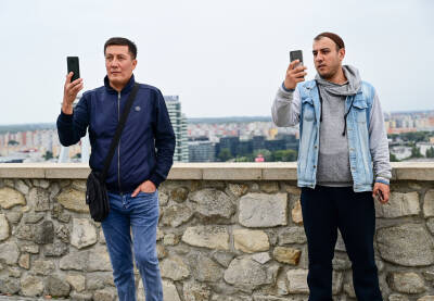 Dvojica muškaraca drže mobilne telefone Bratislava, Slovačka: Ljudi fotografiraju mobitelima na dvorcu u starom gradu. Turisti fotografiraju pametnim telefonima.