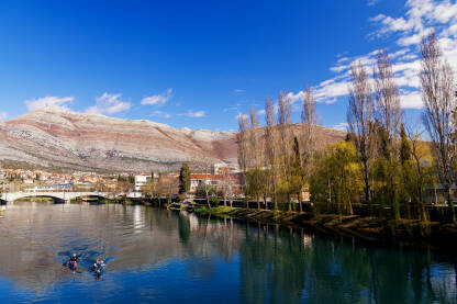 Pogleda na lijevu obalu Trebišnjice, sa kajakašima u prednjem planu. U pozadini se vide "Kameni most" i Leotar